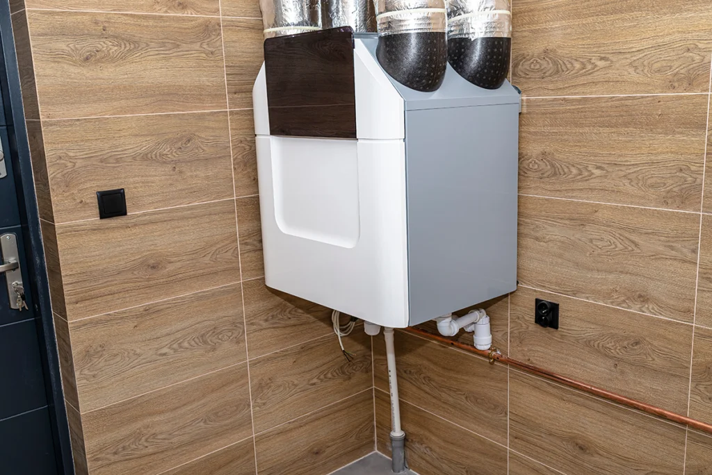 Wall-mounted whole-house ventilation unit with insulated duct connections installed in a mechanical room. Best for blogs about whole-home ventilation systems, fresh air ventilation, HRV vs ERV, indoor air quality systems, stale indoor air problems, and balanced ventilation.