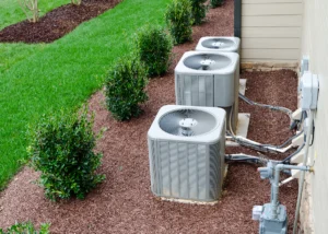 Multiple outdoor residential condenser units installed beside a home with visible refrigerant lines and utility connections. Best for blogs about air conditioning systems, condenser units, HVAC installation, and multi-system residential cooling setups.
