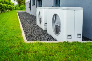 Two outdoor heat pump condenser units installed along the exterior of a residential building.