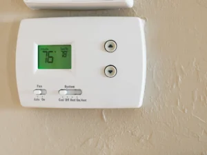 Close-up of a wall-mounted digital thermostat displaying indoor temperature and cooling settings. Best for blogs about how to use a thermostat, thermostat not reaching set temperature, what does hold mean on a thermostat, thermostat troubleshooting, and why your AC or heat keeps running.