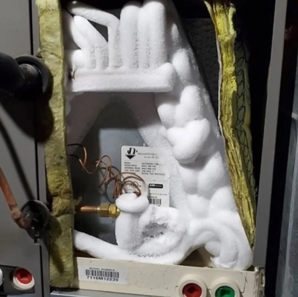 Air conditioner evaporator coil freezing over reducing cooling in Gastonia, NC: close-up of ice buildup on indoor HVAC