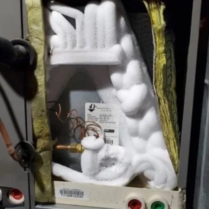 Air conditioner evaporator coil freezing over reducing cooling in Gastonia, NC: close-up of ice buildup on indoor HVAC