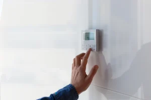 Furnace thermostat not reading temperature correctly in Charlotte NC: a person adjusting a digital programmable thermostat